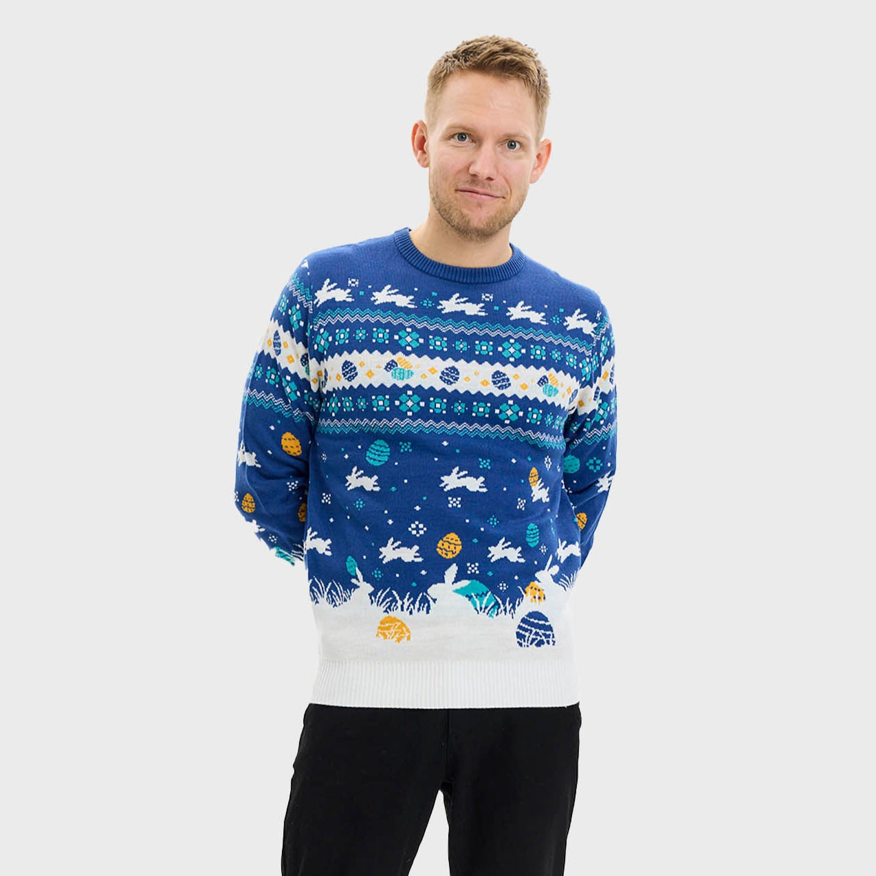 En mann poserer iført en blå påskegenser med kaniner på.